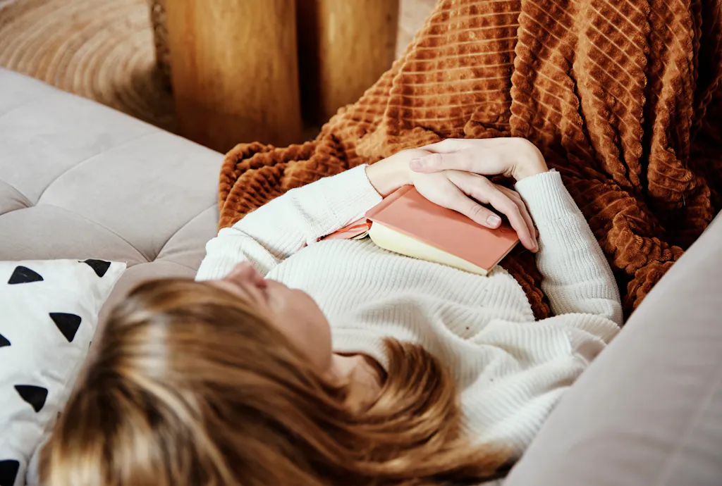 Kobieta leżąca na kanapie z bólem brzucha