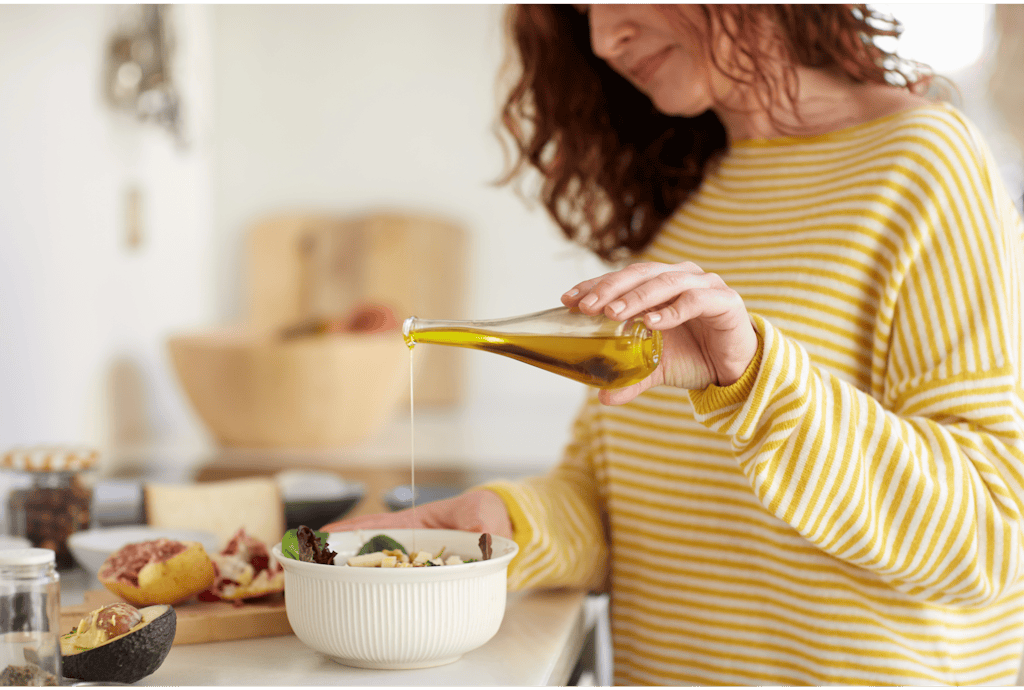 Kobieta dodająca oliwę z oliwek do sałatki Kobieta dodająca oliwę z oliwek do sałatki