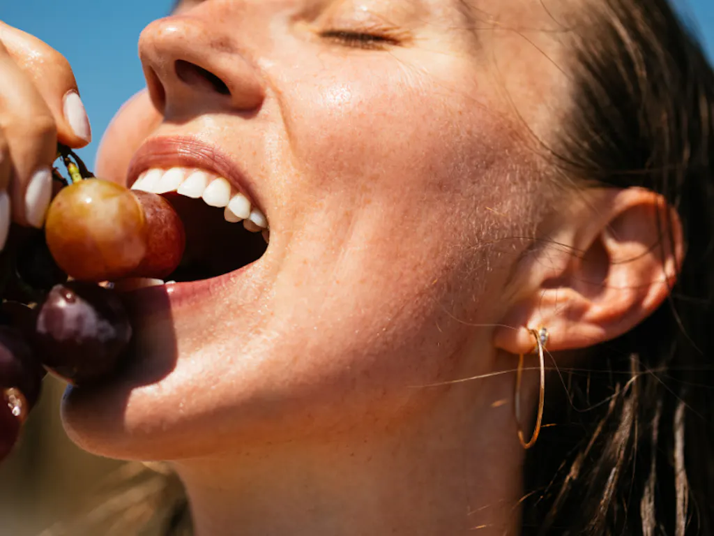 Szczęśliwa kobieta jedząca winogrona