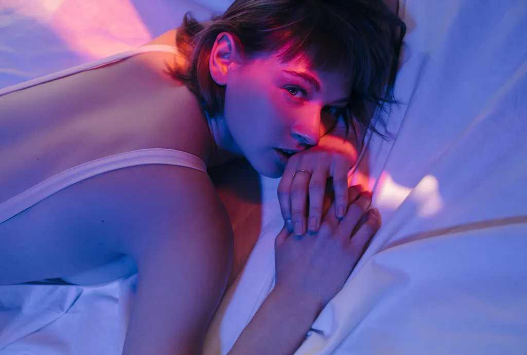 Kobieta leżąca na łóżku w fioletowym świetle