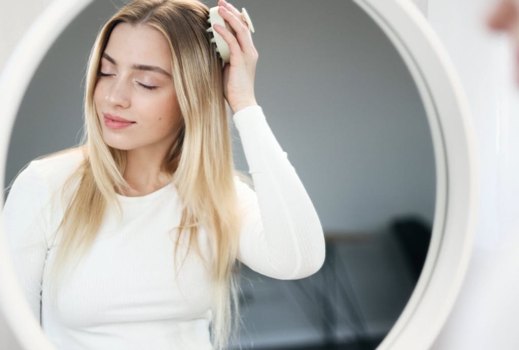 Kobieta stymulująca porost włosów szczotką do masażu głowy Kobieta stymulująca porost włosów szczotką do masażu głowy