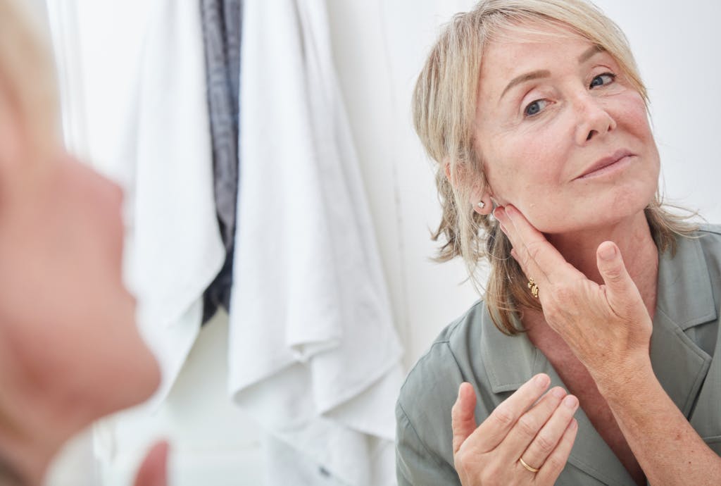 Dojrzała kobieta przeglądająca się w lustrze Dojrzała kobieta przeglądająca się w lustrze