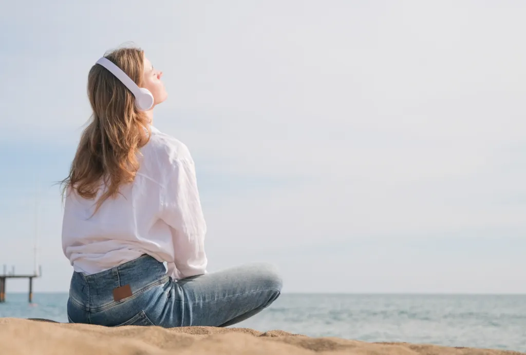 Odpoczywająca kobieta, słuchająca muzyki na plaży