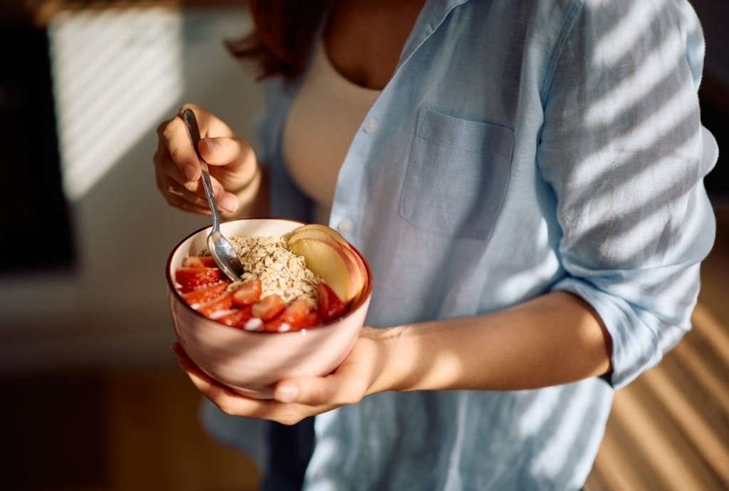 Kobieta trzymająca miskę z owocami zawierającymi błonnik pokarmowy
