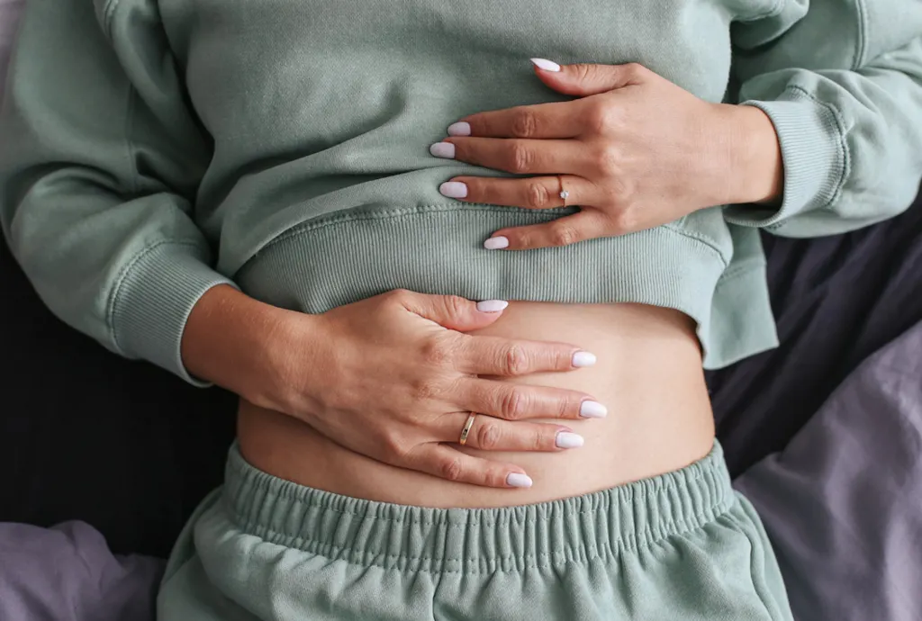 Leżąca kobieta z PCOS, dotykająca brzucha