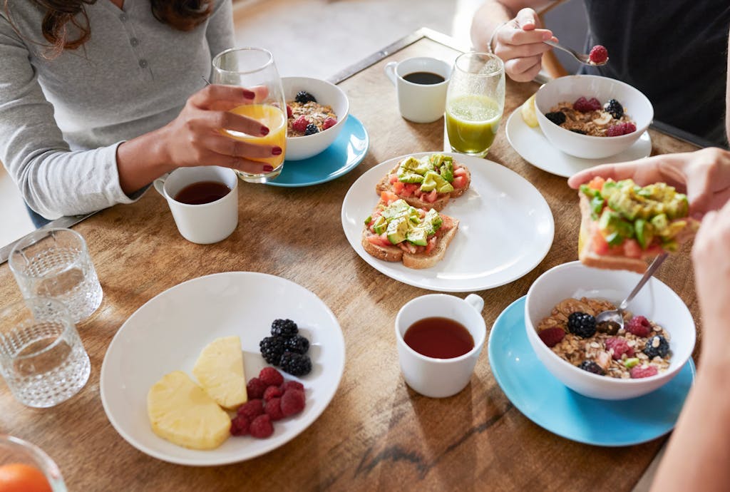 Ludzie spożywający posiłek przy stole zastawionym jedzeniem