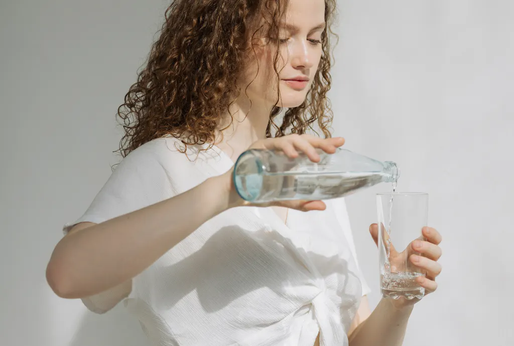 Kobieta nalewająca wodę do szklanki dbająca o zdrowy styl życia